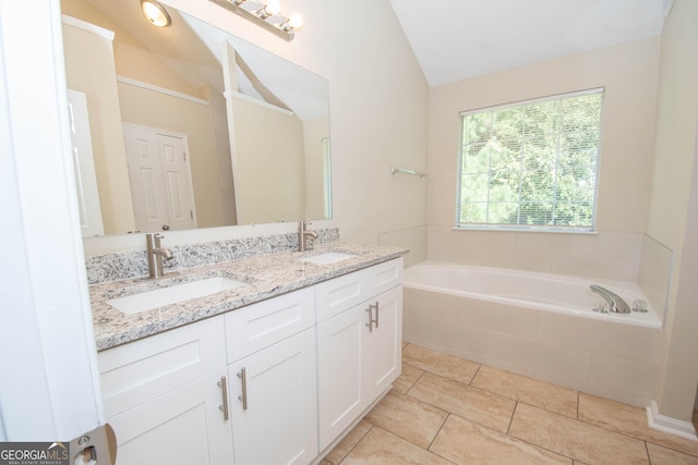 bathroom with double vanity, a garden tub, vaulted ceiling, and a sink