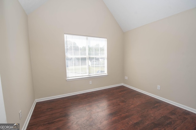 spare room featuring dark wood finished floors, vaulted ceiling, and baseboards