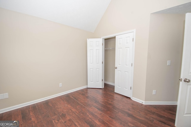 unfurnished bedroom featuring baseboards, vaulted ceiling, a closet, and wood finished floors