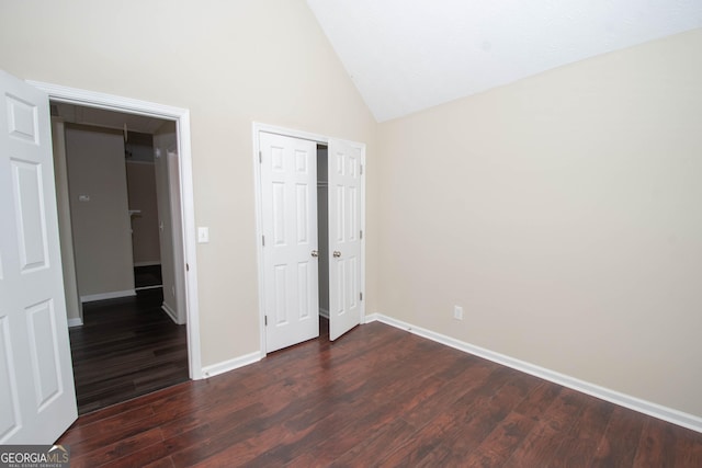 unfurnished bedroom with a closet, dark wood-type flooring, baseboards, and high vaulted ceiling