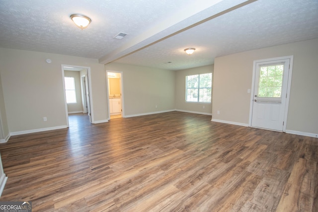 unfurnished living room with a textured ceiling, baseboards, and visible vents