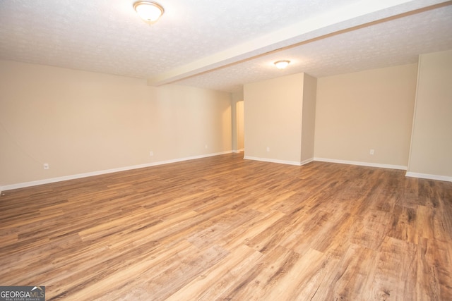 interior space featuring baseboards, a textured ceiling, and wood finished floors