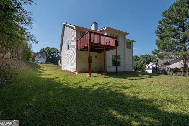back of house with a lawn, a deck, and a chimney