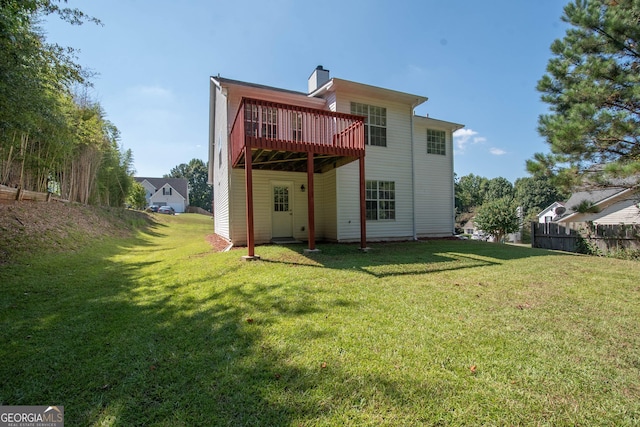 back of house featuring a yard, a deck, fence, and a chimney