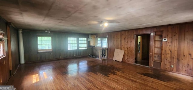 empty room featuring wood walls, plenty of natural light, and wood finished floors