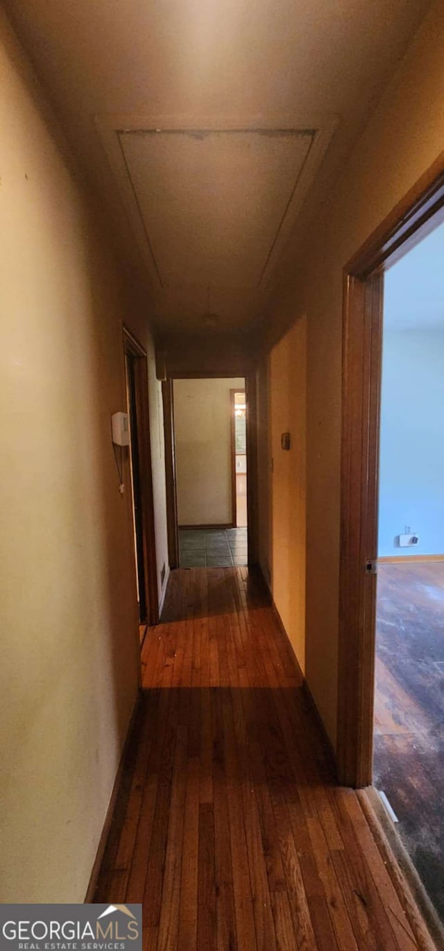 hallway with attic access and wood-type flooring
