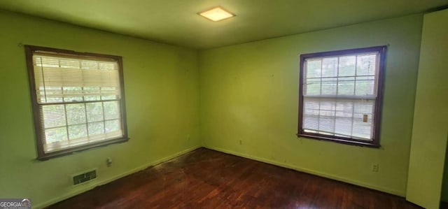 spare room with baseboards, visible vents, and wood finished floors
