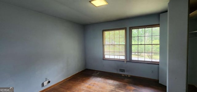 unfurnished room with baseboards, visible vents, and wood finished floors
