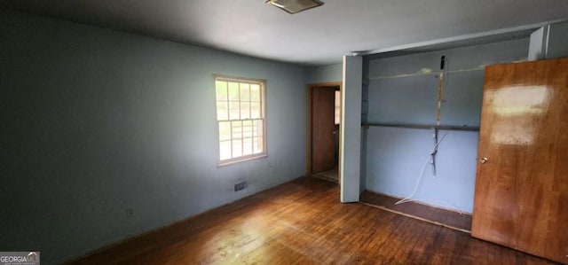 unfurnished bedroom featuring a closet, visible vents, and wood finished floors