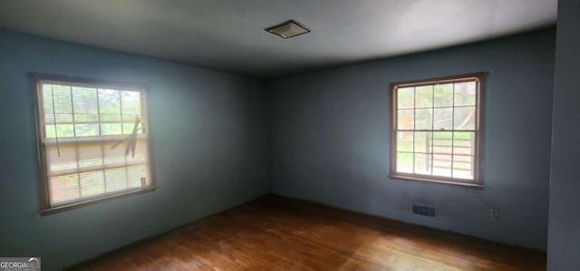 spare room with plenty of natural light and wood finished floors