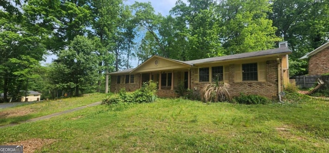 ranch-style house with a front lawn, brick siding, a chimney, and fence