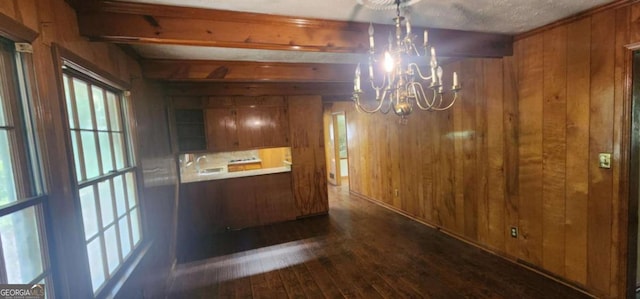 unfurnished dining area with wooden walls, dark wood-type flooring, and a notable chandelier