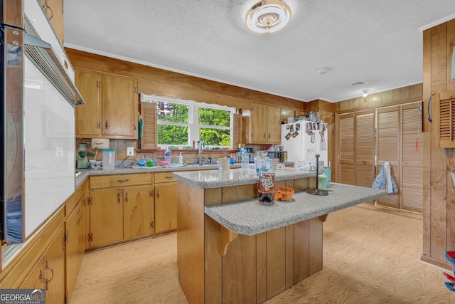 kitchen with wall oven, light countertops, light wood-style flooring, and a textured ceiling