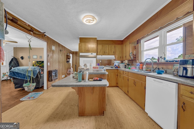 kitchen with a sink, white appliances, a textured ceiling, light wood finished floors, and a kitchen bar