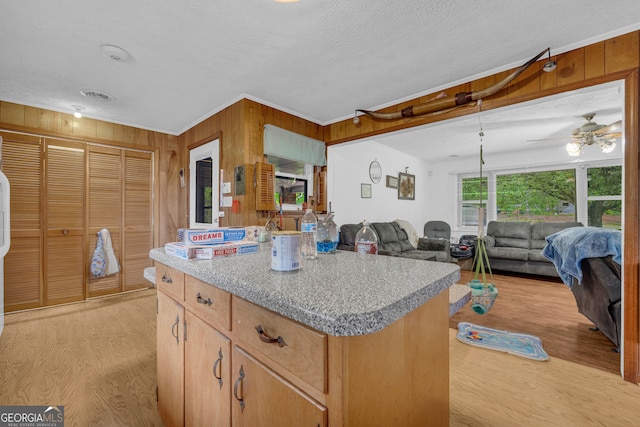 kitchen featuring a center island, light countertops, wooden walls, and light wood-style flooring