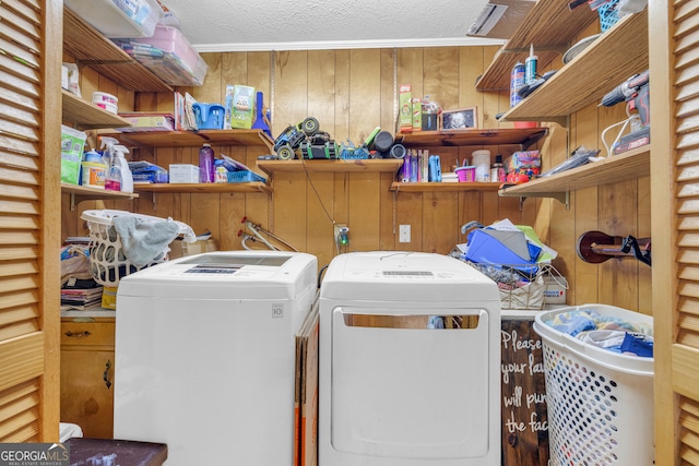 laundry area featuring washing machine and dryer, laundry area, wood walls, and a textured ceiling