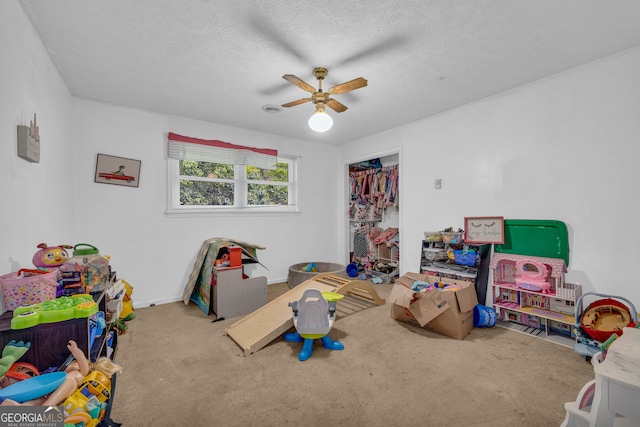 playroom featuring ceiling fan, a textured ceiling, carpet floors, and baseboards