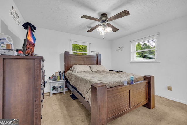 bedroom with a textured ceiling, light carpet, baseboards, and ceiling fan