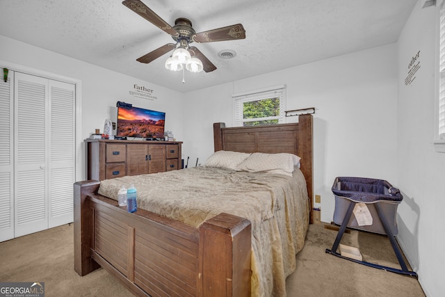 bedroom featuring a textured ceiling, a closet, ceiling fan, and light colored carpet