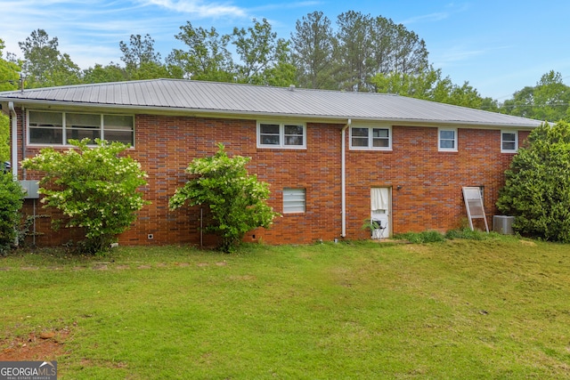 rear view of property with a lawn, central air condition unit, and brick siding