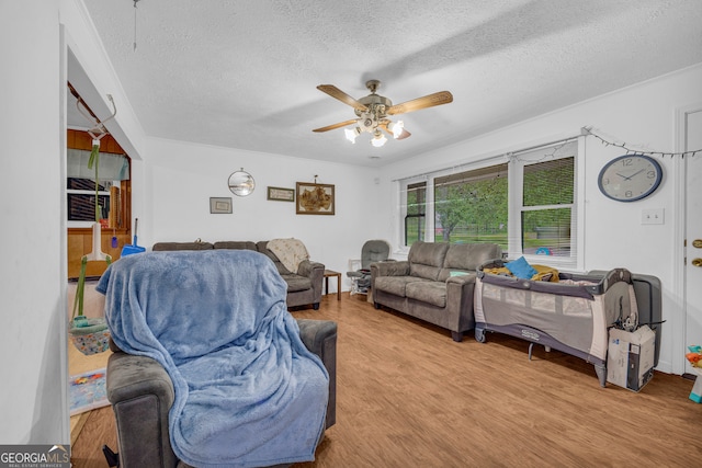 living area featuring a textured ceiling, a ceiling fan, and wood finished floors
