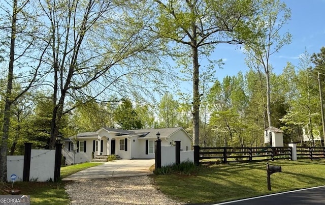 ranch-style home with concrete driveway, a fenced front yard, and stucco siding
