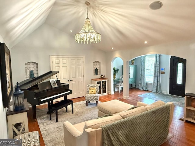 living area featuring arched walkways, a chandelier, lofted ceiling, wood finished floors, and recessed lighting