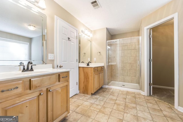 bathroom with a sink, two vanities, a stall shower, and visible vents