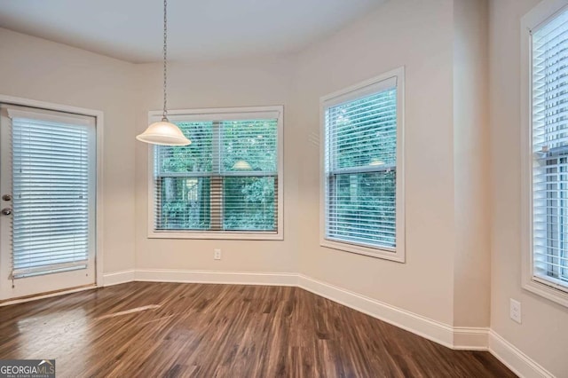 unfurnished dining area with dark wood finished floors and baseboards