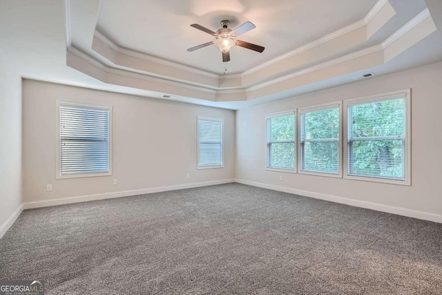 empty room with crown molding, a raised ceiling, carpet floors, and a ceiling fan