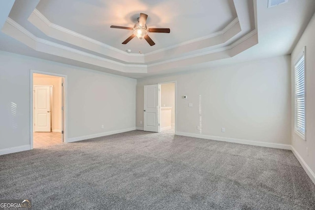 unfurnished bedroom featuring carpet flooring, baseboards, a raised ceiling, and ornamental molding
