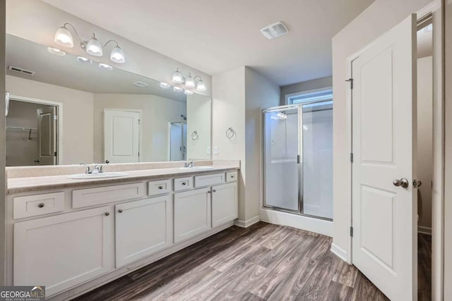 bathroom with a stall shower, visible vents, a sink, and wood finished floors