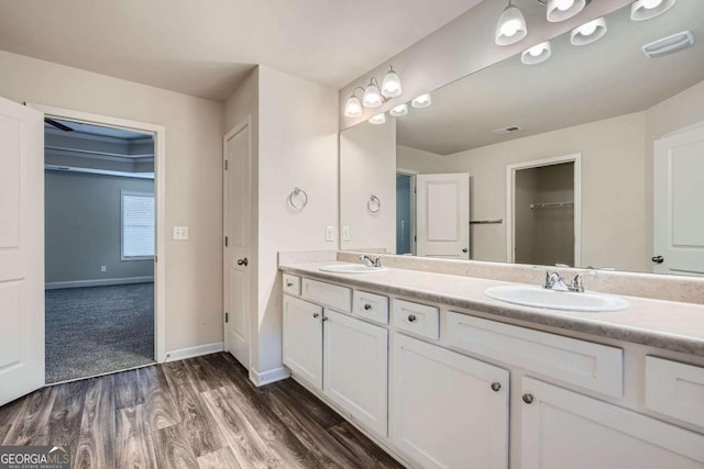 full bathroom featuring a sink, double vanity, visible vents, and wood finished floors