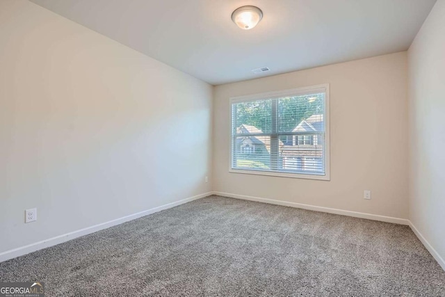 spare room featuring baseboards, visible vents, and carpet