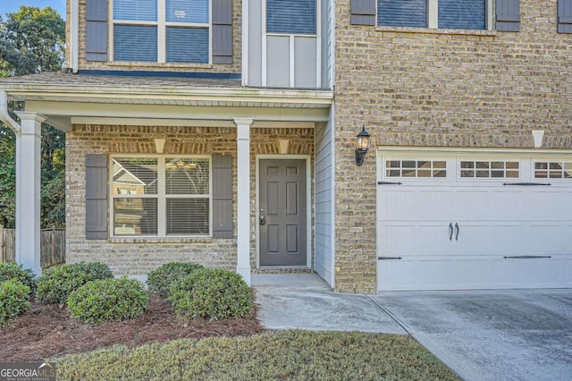 view of exterior entry featuring driveway, a porch, brick siding, and a garage