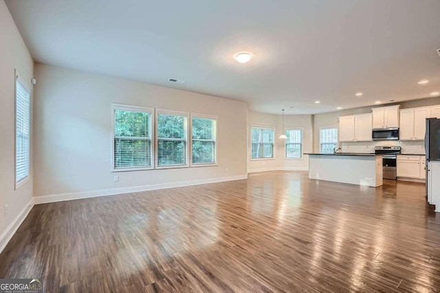 unfurnished living room with recessed lighting, visible vents, baseboards, and dark wood-style floors