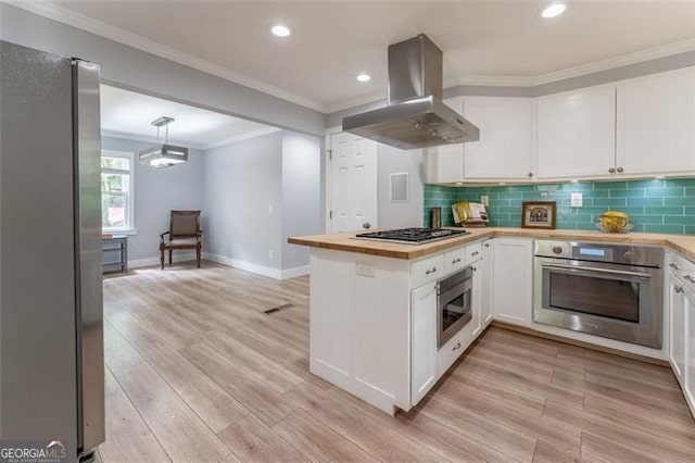 kitchen featuring island exhaust hood, wood counters, white cabinets, baseboards, and appliances with stainless steel finishes