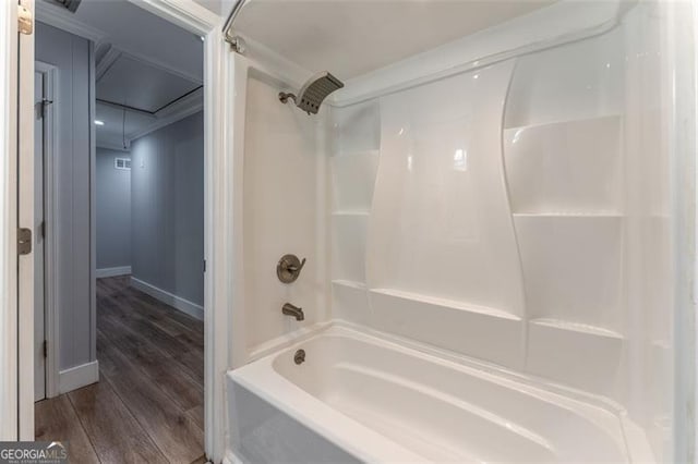 full bathroom featuring baseboards, wood finished floors, and shower / tub combination