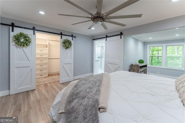 bedroom with a barn door, recessed lighting, crown molding, baseboards, and light wood-style floors