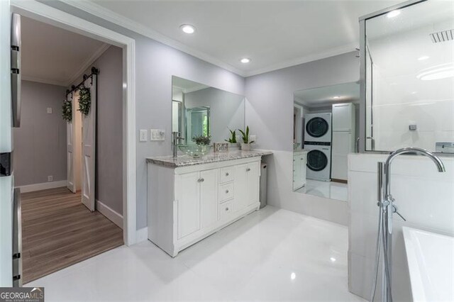 bathroom with recessed lighting, vanity, crown molding, a soaking tub, and stacked washer / drying machine