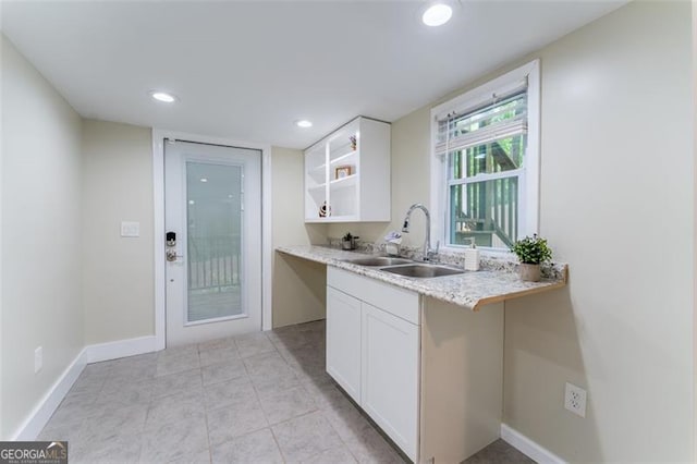 kitchen featuring recessed lighting, light countertops, white cabinetry, and a sink
