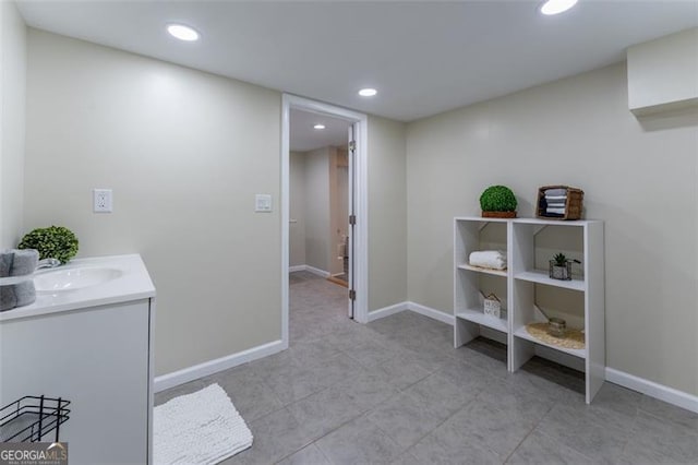 corridor with baseboards, light tile patterned floors, recessed lighting, and a sink