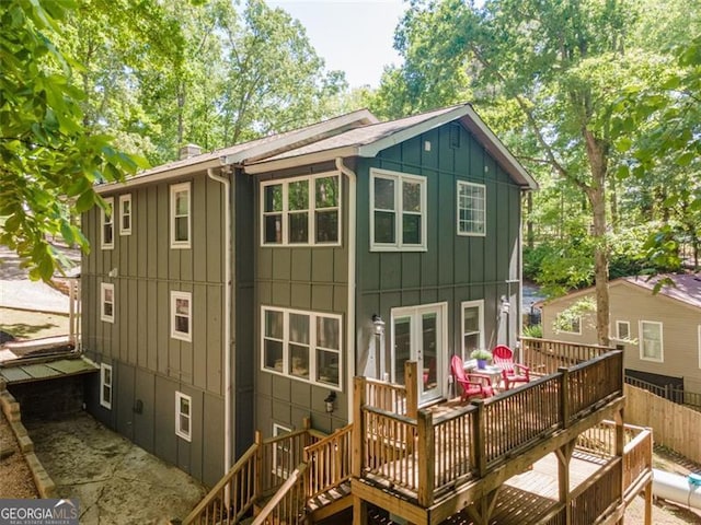 rear view of property featuring board and batten siding, french doors, fence, stairs, and a deck