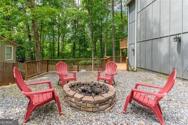 view of patio with a deck, a fire pit, and fence