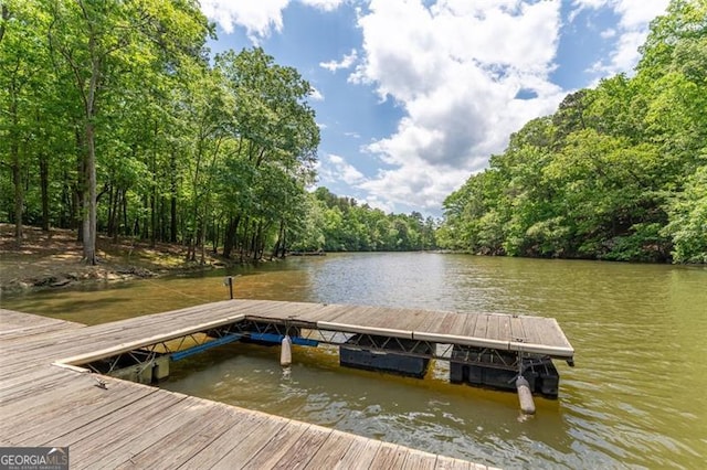 view of dock with a wooded view and a water view