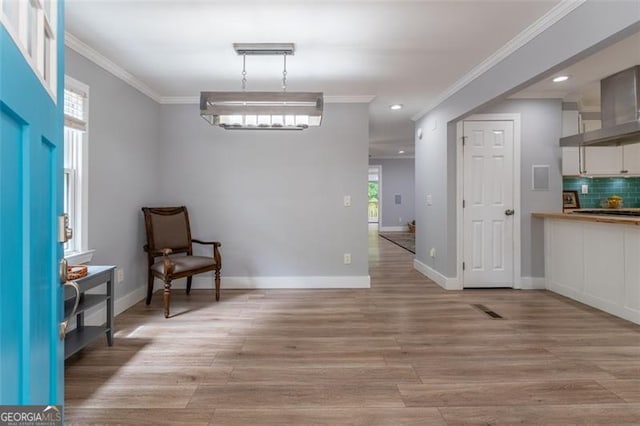 living area with baseboards, ornamental molding, recessed lighting, and light wood-style floors