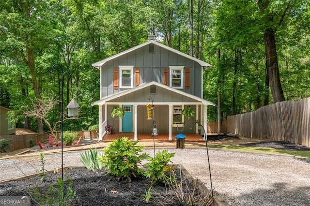 view of front of house with board and batten siding, a porch, and fence private yard