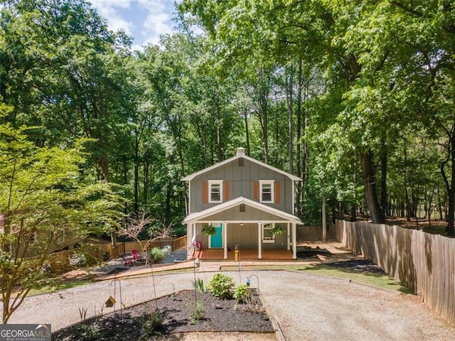 view of front facade with covered porch, fence, driveway, and board and batten siding