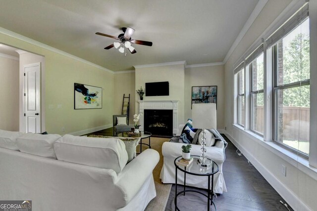 living room with dark wood-style flooring, baseboards, a fireplace, ornamental molding, and ceiling fan