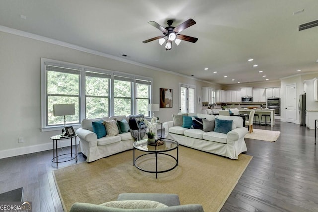 living area with ornamental molding, a ceiling fan, baseboards, recessed lighting, and dark wood-style floors